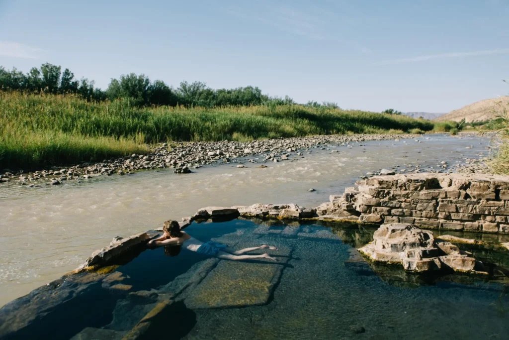 Man in relaxing in hot springs overlooking Rio Grande river in the morning