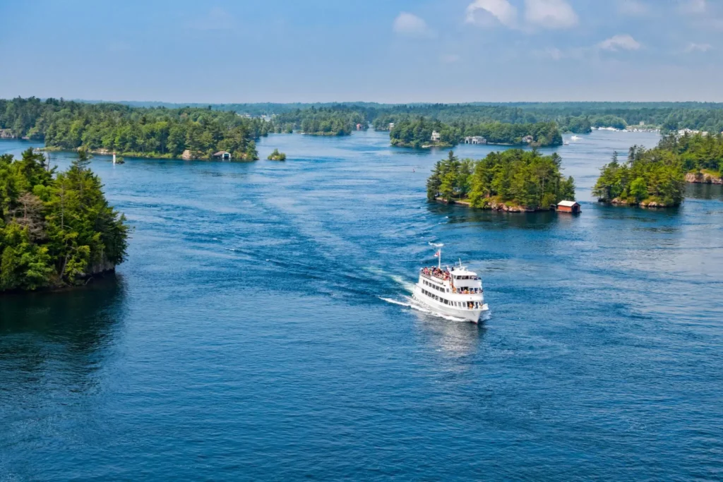 a tour boat with tourists passing between islands at Thousand Islands National Park, St Lawrence River, located between Ontario Canada and New York State USA
