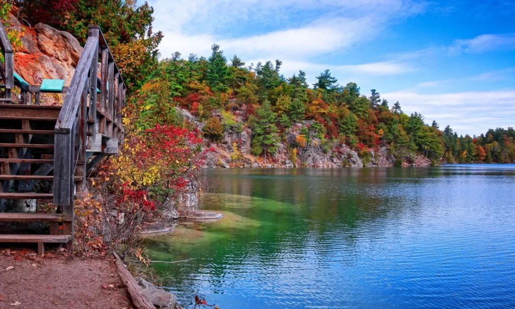 Hiking trail along Pink Lake, Gatineau Park in autumn with reflections of fall colors. 