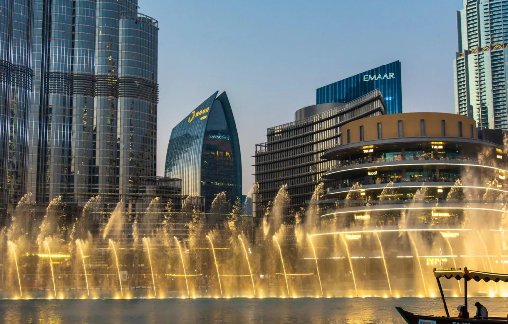Dubai fountain show in front of Dubai mall shopping and leisure area surrounded and modern downtown buildings in the United Arab Emirates at blue hour
